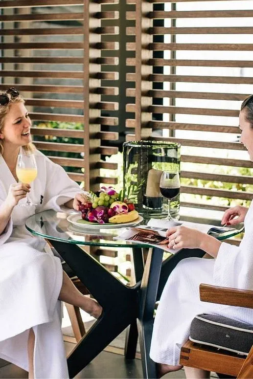 Dos personas comparten una comida junto a una celosía de madera.